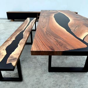 Könnte beinhalten: Ein Esstisch- und Bänkeset aus Holz mit schwarzem Epoxidharzeinlage. Tisch und Bank haben schwarze Metallbeine.