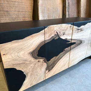 May include: A black cabinet with three doors made of wood with black resin inlay. The wood has a natural grain pattern.