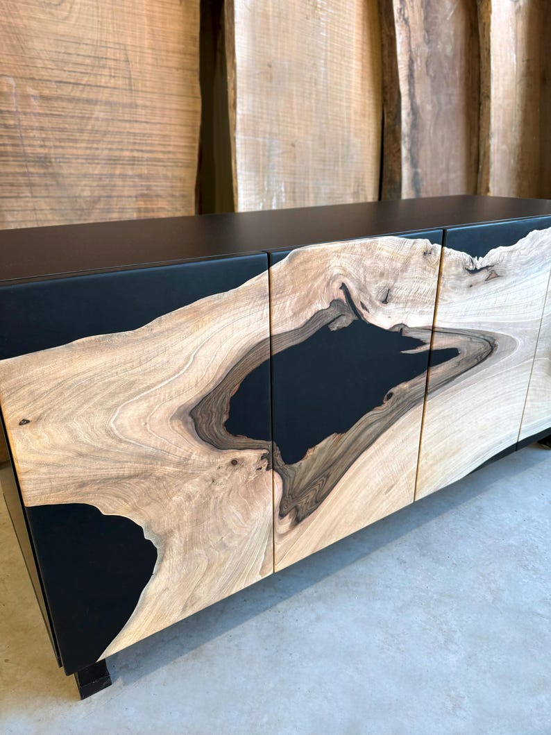 May include: A black cabinet with three doors made of wood with black resin inlay. The wood has a natural grain pattern.