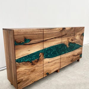 May include: A wooden cabinet with three doors and a green epoxy resin inlay. The cabinet has a natural wood finish and is made of solid wood.