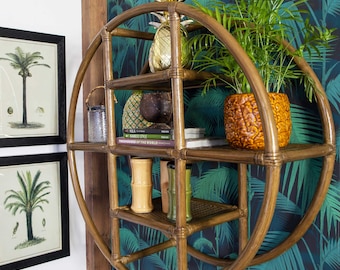 May include: A round, wooden shelf with four shelves. The shelf is decorated with a pineapple, a potted plant, and books. The shelf is mounted on a wall with a tropical wallpaper.