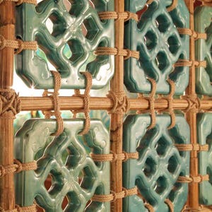 Puede incluir: Una pantalla decorativa con paneles rectangulares turquesas con intrincados diseños calados. Los paneles están enmarcados por bambú natural y asegurados con cuerdas anudadas, creando un patrón visualmente atractivo. Ideal para el diseño de interiores.