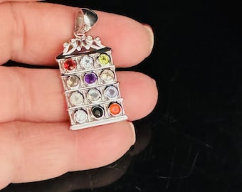May include: Silver pendant with a tower design featuring nine colorful gemstones. The gemstones are arranged in a vertical row and include red, orange, yellow, green, blue, purple, white, black, and clear.