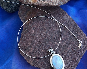 May include: A silver chain necklace with a silver oval pendant featuring a moonstone. The pendant has an intricate design around the stone.