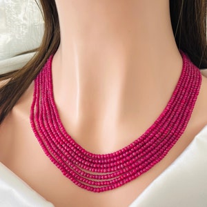May include: A multi-strand necklace made of small, faceted ruby beads. The necklace is layered and creates a bold statement.