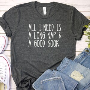 May include: A dark gray t-shirt with the text "All I need is a long nap & a good book" printed in white.