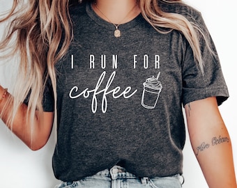 May include: Dark gray t-shirt with the text "I RUN FOR coffee" in white script. A white line drawing of a coffee drink with a straw is next to the text. The shirt is a crew neck style.