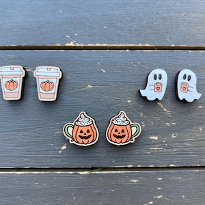 May include: A set of six wooden earrings featuring fall-themed designs. Two earrings are pumpkin spice latte cups, two are ghosts holding latte cups, and two are pumpkin spice latte cups with a jack-o-lantern face.