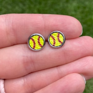 May include: A pair of silver stud earrings with a yellow and red softball design.