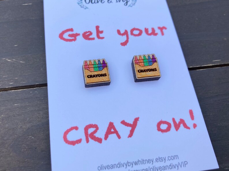 K&ouml;nnte beinhalten: Eine wei&szlig;e Karte mit dem Text "Get your Cray on!" und zwei kleine Holzkisten mit dem Wort "Crayons" und einem Regenbogen aus Buntstiften darauf.