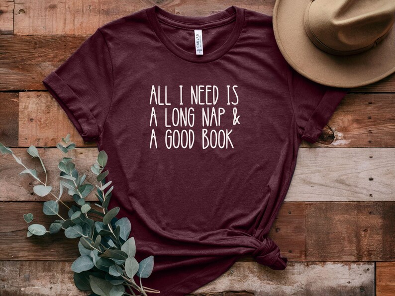 May include: Burgundy t-shirt with white text that reads "All I need is a long nap & a good book".