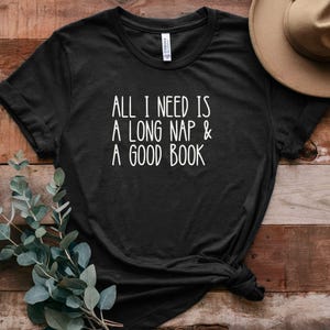 May include: Black t-shirt with white text that reads "All I need is a long nap & a good book".