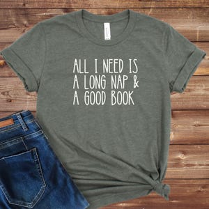 May include: A green t-shirt with the text "All I need is a long nap & a good book" printed in white.