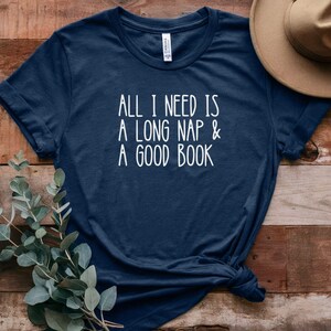 May include: A navy blue t-shirt with the text "All I need is a long nap & a good book" printed in white.