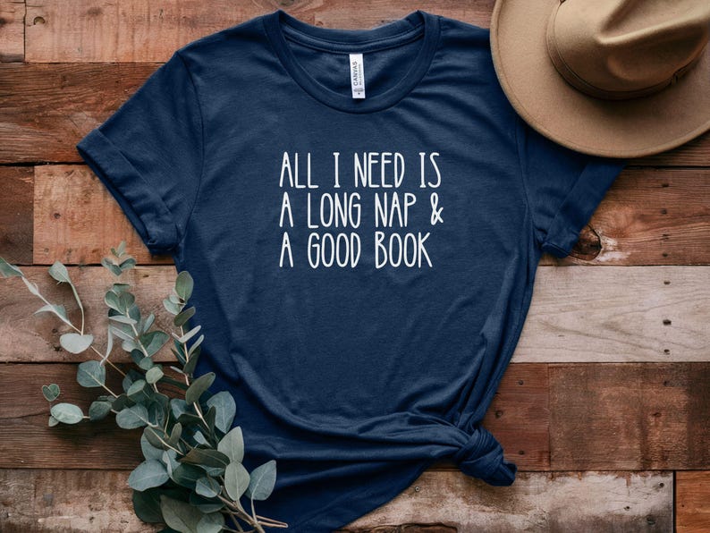 May include: A navy blue t-shirt with the text "All I need is a long nap & a good book" printed in white.