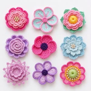 May include: A collection of nine handcrafted crochet flowers in various colors and designs. The set includes blossoms in shades of pink, purple, blue, and green, some featuring central pearl-like beads or textured centers, arranged in a grid pattern.