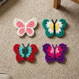 May include: Four handmade crochet butterfly appliques in various color combinations. One is white and pink, one is teal, white, and yellow with black antennae, one is red and light blue, and one is purple and pink with dark purple antennae.