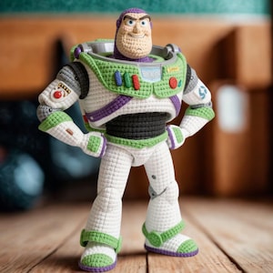 Op de afbeelding: Een handgemaakte Buzz Lightyear-pop gehaakt, staand op een houten oppervlak. De pop heeft een wit ruimtepak met groene en paarse accenten, een zwarte torso en een lachend gezicht. De armen van de pop hangen langs de zijkanten.