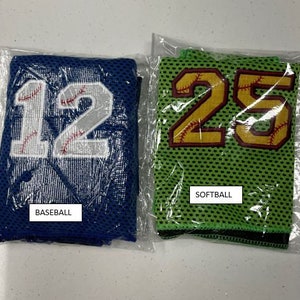 May include: Two mesh baseball and softball jerseys in plastic packaging. The baseball jersey is blue with the number 12 in white and red stitching. The softball jersey is green with the number 25 in gold and red stitching. The word "BASEBALL" and "SOFTBALL" are printed on the packaging.