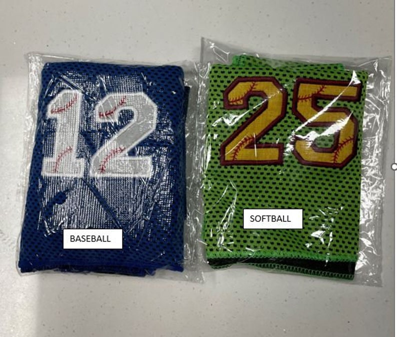 May include: Two mesh baseball and softball jerseys in plastic packaging. The baseball jersey is blue with the number 12 in white and red stitching. The softball jersey is green with the number 25 in gold and red stitching. The word "BASEBALL" and "SOFTBALL" are printed on the packaging.