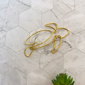 May include: Gold wire sculpture of a turtle on a white marble background.