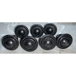 May include: Set of seven black round cabinet knobs with a concentric circle design.