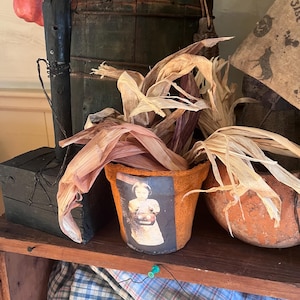 Primitieve halloweenpot met label gedroogde maïskolven en heks