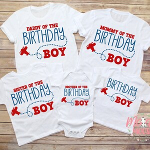 May include: Set of four white t-shirts with red and blue text that says "Daddy of the Birthday Boy", "Mommy of the Birthday Boy", "Sister of the Birthday Boy", and "Brother of the Birthday Boy". Each shirt features a red aeroplane with a blue dotted line.