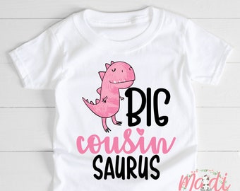 May include: White t-shirt with a pink dinosaur graphic and the text "BIG COUSIN SAURUS".
