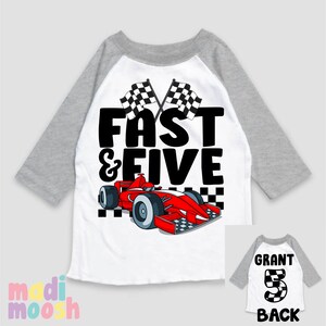 May include: A white and grey baseball style t-shirt with a red race car and chequered flags. The text "Fast & Five" is printed on the front of the shirt. The back of the shirt has the text "Grant 5" printed on it.