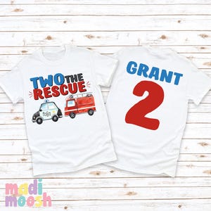 May include: White t-shirt with the text "Two the Rescue" and a cartoon police car and fire truck. The back of the shirt has the name "Grant" and the number "2" in red.