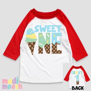 May include: White and red baseball style shirt with the text "SWEET ONE" in blue, green, and brown letters. The letters are decorated with a brown waffle cone pattern and a blue, green, and yellow ice cream cone graphic. The back of the shirt is red and white with the text "GRANT 1" in brown letters.