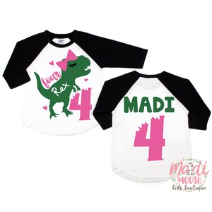 May include: Two white and black baseball shirts with green and pink dinosaur graphics. The front shirt has a green dinosaur with a pink bow and the text "four Rex". The back shirt has the text "MADI" and a pink number "4".