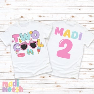 May include: Two white t-shirts with colorful graphics. One shirt says "TWO COOL" with sunglasses, a flamingo float, and other summer icons. The other shirt says "MADI 2" in pink, blue, and purple.
