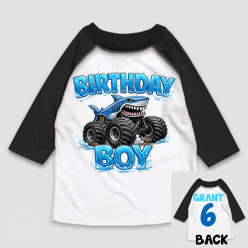 May include: White and black raglan-sleeve shirt with a blue shark monster truck graphic. The shirt says "BIRTHDAY BOY" in blue letters. The back of the shirt has the name "GRANT", the number "6", and the word "BACK".