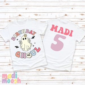 May include: White t-shirt with a ghost wearing a flower crown and the text "Birthday Ghoul" in rainbow colours. The back of the shirt has the name "MADI" and the number "5" in pink.