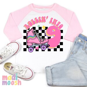 May include: A pink and white baseball tee shirt with a pink roller skate and the text "Rollin' into 9" on a black and white checkered background.