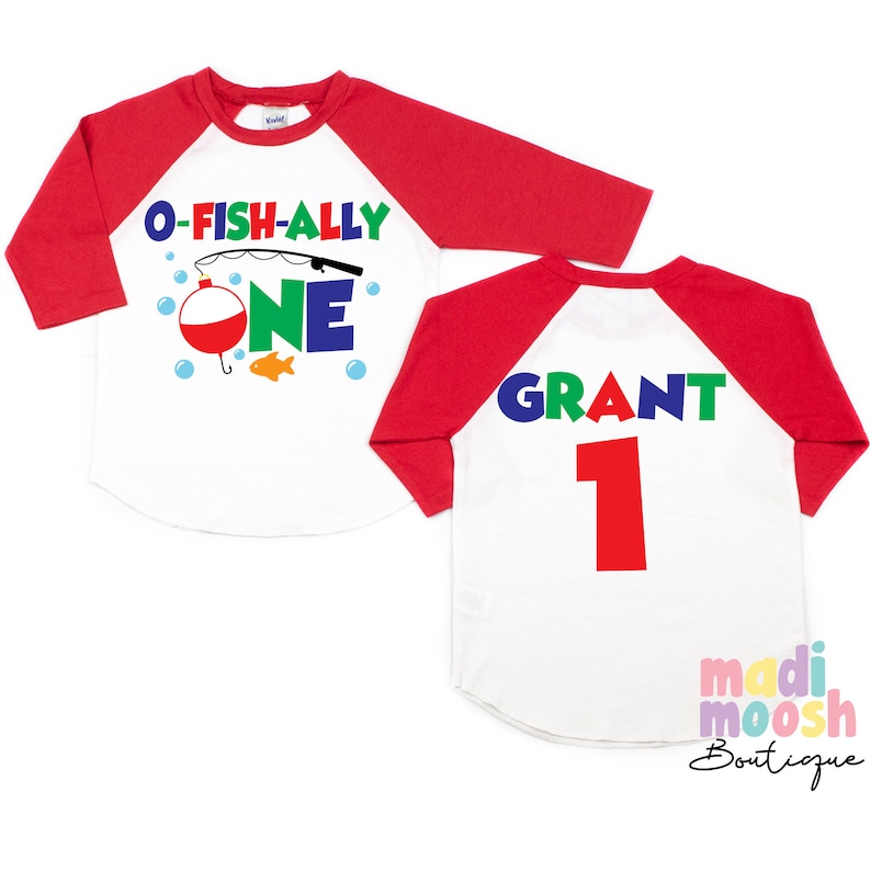 May include: A white and red raglan style shirt with the text "O-Fish-Ally One" and a fishing theme graphic on the front. The back of the shirt has the name "Grant" and the number "1" printed on it.