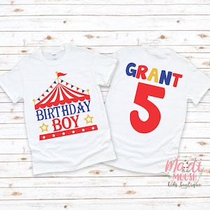 May include: White t-shirt with a red, white and blue circus tent graphic and the text "Birthday Boy" on the front. The back of the shirt has the name "GRANT" in colourful letters and the number "5" in red.