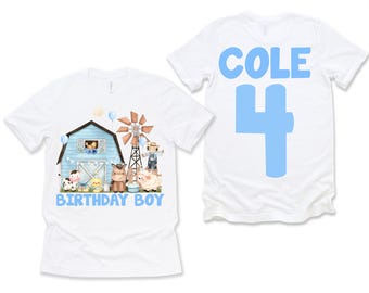 May include: White t-shirt with a blue barn, windmill, and farm animals on the front. The back of the shirt has the name "COLE" and the number "4" in blue.