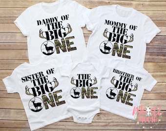 May include: White t-shirts with a camouflage design and the text "Daddy of the Big One", "Mommy of the Big One", "Sister of the Big One", "Brother of the Big One", and "The Big One".