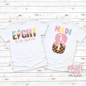 May include: White t-shirt with the text "EIGHT is so sweet" in pink, yellow, and blue with an ice cream cone graphic. The back of the shirt has the name "MADI" in rainbow colors and a pink number 8 with sprinkles and a waffle cone graphic. The shirt has the text "madi moosh kids boutique" in the bottom right corner.