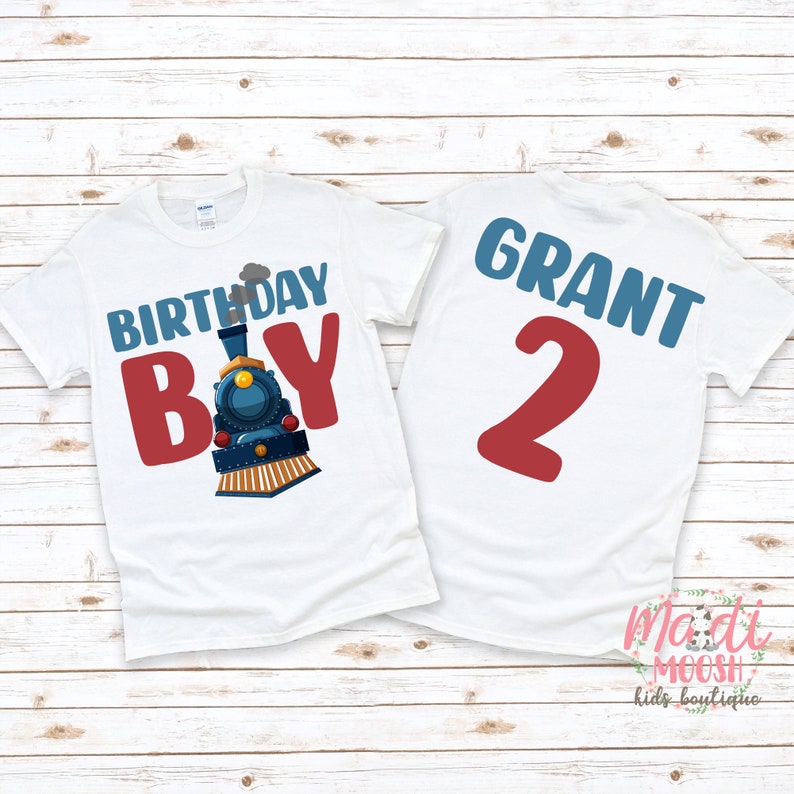May include: White t-shirt with a blue train and the text "Birthday Boy" in red. The back of the shirt has the name "Grant" and the number "2" in red.