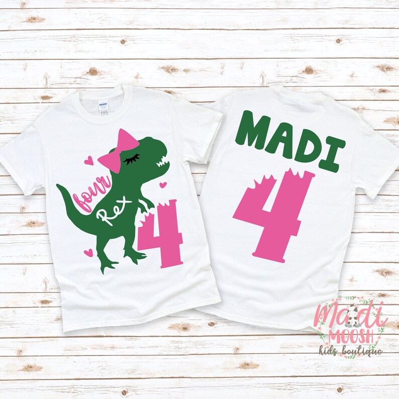 May include: White t-shirt with a green dinosaur wearing a pink bow and the text "four Rex" and a pink number 4. The back of the shirt has the name "MADI" in green letters and a pink number 4.