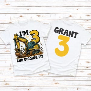 May include: Two white t-shirts with a construction theme. One shirt features a yellow excavator with the text "I'M 3 AND DIGGING IT!". The other shirt has the name "GRANT" and the number "3" in yellow.