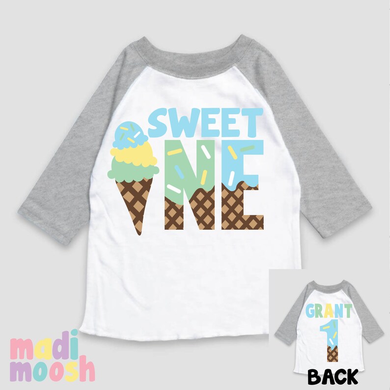 May include: White and grey baseball tee shirt with the words "Sweet One" in blue, green, and brown. The "One" is designed to look like an ice cream cone. The back of the shirt has a grey baseball tee with the word "Grant" and the number "1" in brown. The number "1" is also designed to look like an ice cream cone.