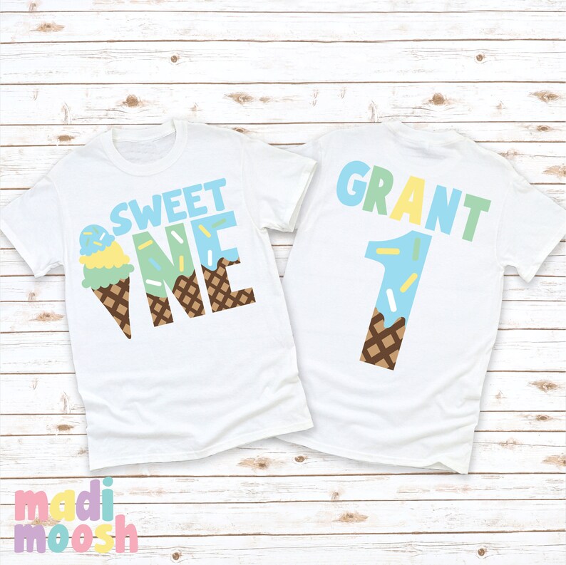 May include: Two white t-shirts with an ice cream cone design. The front shirt says "Sweet One" with the ice cream cone forming the "O" in "One". The back shirt says "Grant 1" with the ice cream cone forming the number "1".
