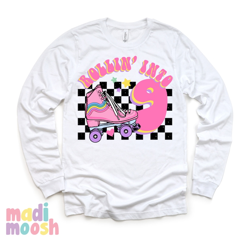 May include: White long-sleeve shirt with a pink roller skate and the text "Rollin' into 9" in a retro font. The background is a black and white checkered pattern with stars.