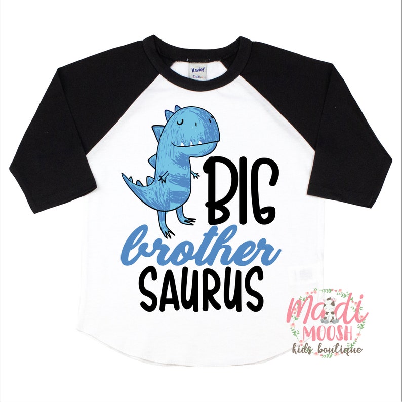 May include: A white and black baseball tee shirt with a blue dinosaur graphic and the text "BIG brother SAURUS".