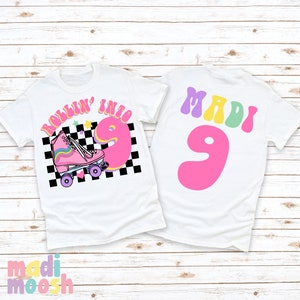 May include: Two white t-shirts with a roller skate design. The front shirt has a pink roller skate with rainbow laces and the text "Rollin' into 9". The back shirt has the text "MADI 9" in colorful letters.